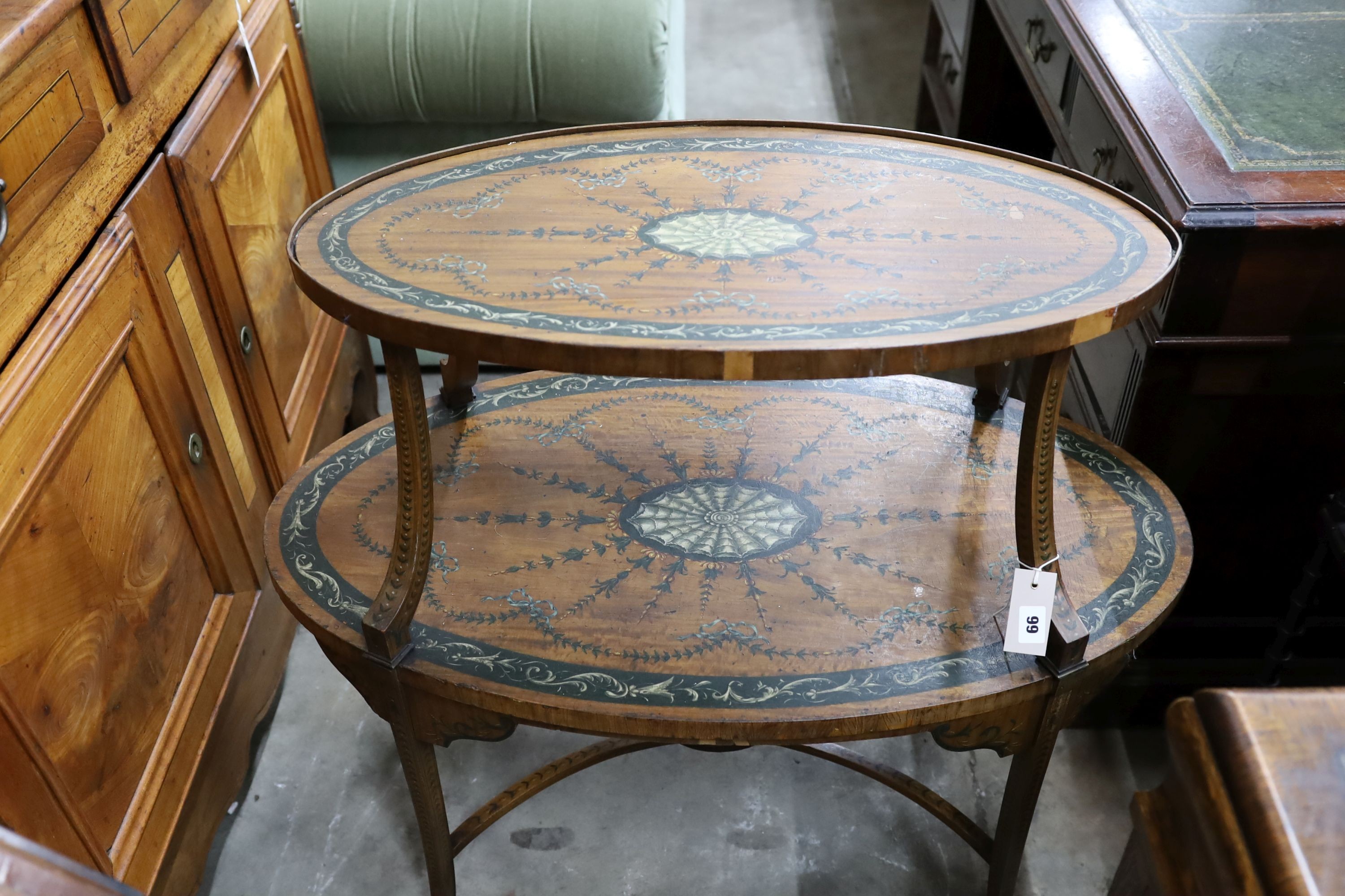 An Edwardian Sheraton revival oval painted satinwood two tier etagere, width 90cm, depth 50cm, height 82cm